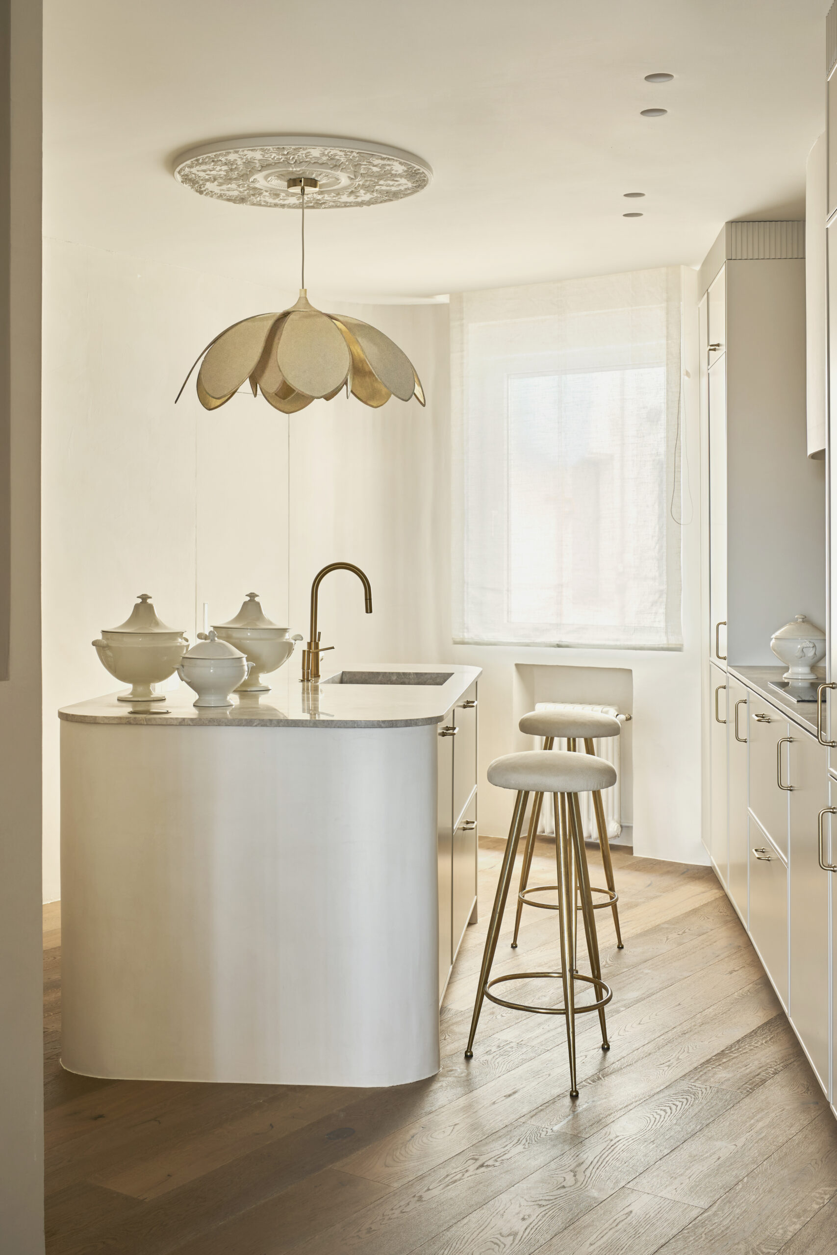 Cocina con suelo de madera color roble, detalles dorados y microcemento